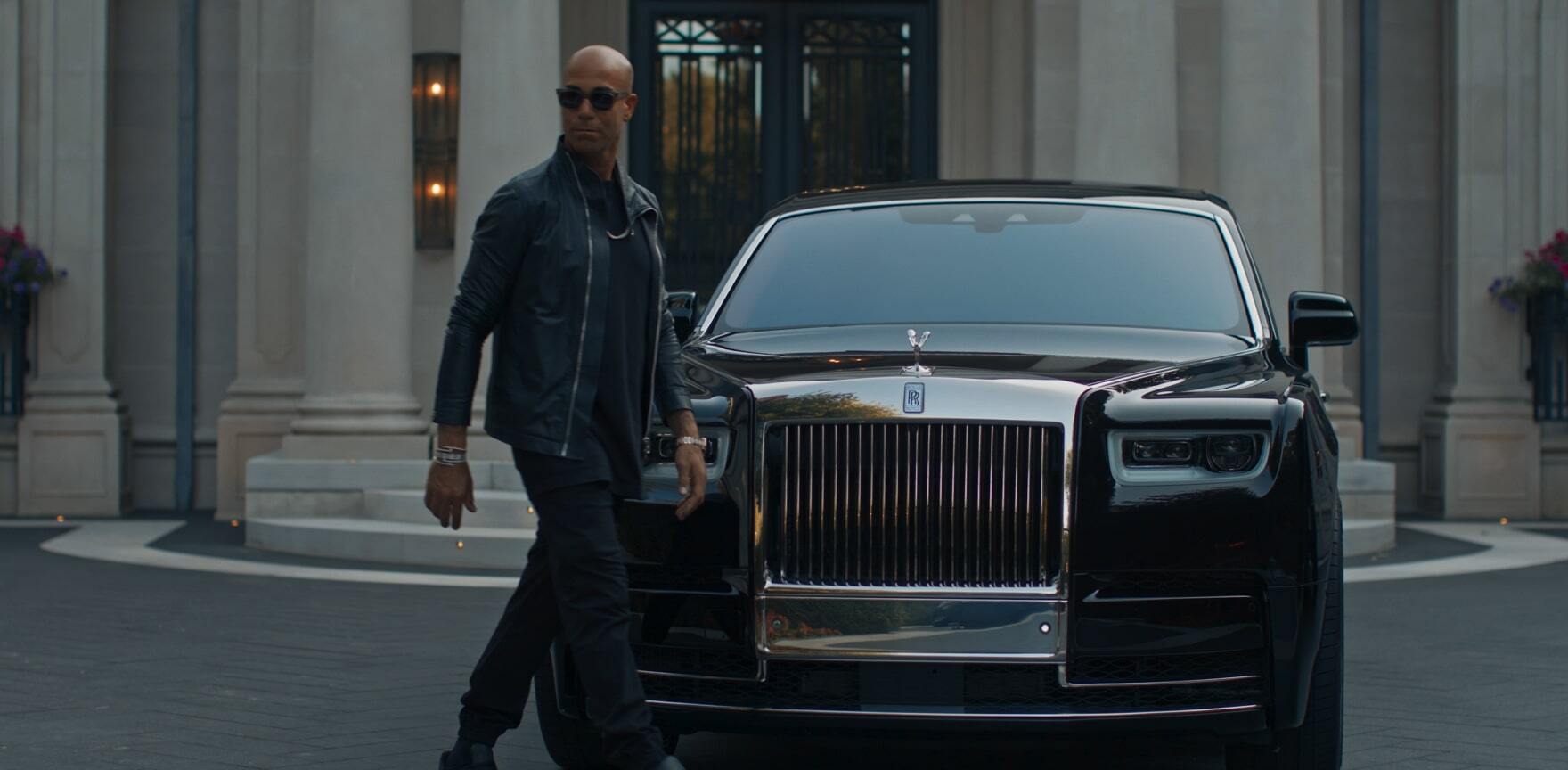 Ferris Rafauli walking next to his Rolls-Royce car
