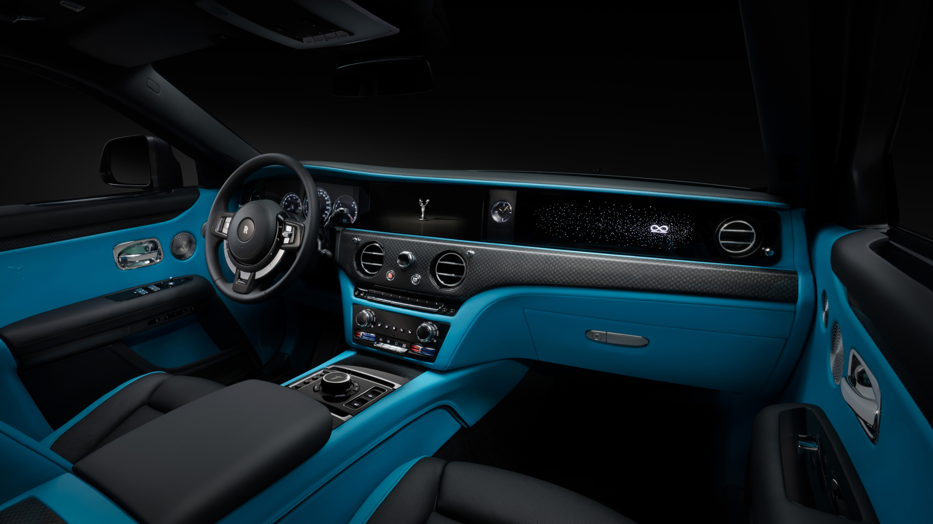 Interior shot of Black Badge Ghost displaying the crisp blue interior, the elegant dashboard and one of a kind steering wheel with the Rolls Royce logo