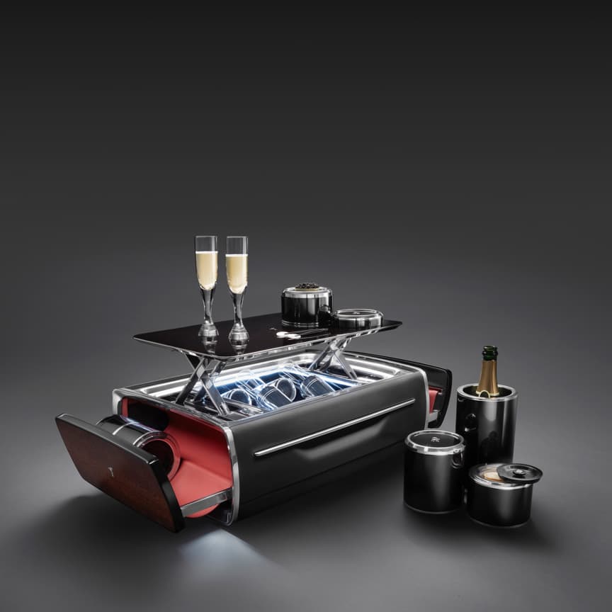 <p>劳斯莱斯香槟酒柜由技艺娴熟的工匠手工精制而成,精彩诠释优雅与奢华,无论置身何种场合,均能成为增添华彩的精品之作。轻启按钮,酒柜缓缓开启,全套香槟酒具就会呈现在眼前,弥散出雍容气度。手工打磨的铝合金底座覆以天然粒面皮革,两侧以精致的实木装饰,与劳斯莱斯车辆用材相呼应,素璞至美,浑然天成。</p>
<p>无论是安置在精致真皮底座上的香槟冷却器,还是四只精巧的手工吹制水晶香槟杯,它们的布局巧妙地呼应了V12发动机的气缸排列,充分展现了劳斯莱斯对每一个细节的追求。</p>
<p>这款香槟酒柜适应多种场景需求,无论是悠游海浪间的奢华旅程,还是私人宅邸的露台聚会,劳斯莱斯香槟酒柜的璨然风采,让人心驰神往。酒柜内每一样器具皆经精心挑选,包括能有效保持香槟冰爽的高效保温瓶,以及精致的珍珠母贝鱼子酱匙,旨在为宾客提供畅享愉悦的难忘时刻。</p>
<p>香槟酒柜包括:</p>
<p>• 可取走的托盘(装在可展开的盖板上)。</p>
<p>• 香槟保温瓶(可容纳至多750毫升的香槟酒瓶)。</p>
<p>• 两个保温鱼子酱碗(可容纳30克鱼子酱罐)和两个食碗,或者一个餐具套装,带三个可单独取用的瓷碗。</p>
<p>• 珍珠母贝鱼子酱匙。</p>
<p>• 四条带有刺绣图案的餐巾。</p>
<p>• 四支手工吹制的香槟酒杯。</p>
<p>• 皮革外罩。</p>
<p>• 带适配器的电源充电线,可以适用于不同地区。</p>
<p>• 适用12伏电源的充电线。</p>
<p>此外,我们还提供一个精美的小食碗或一组配套的鱼子酱餐具套装。更多详情,欢迎咨询您的经销商。</p>
<p>图示为主推配置。同时,您还可以根据劳斯莱斯的内部装饰风格,对香槟酒柜进行个性化的高级定制。</p>