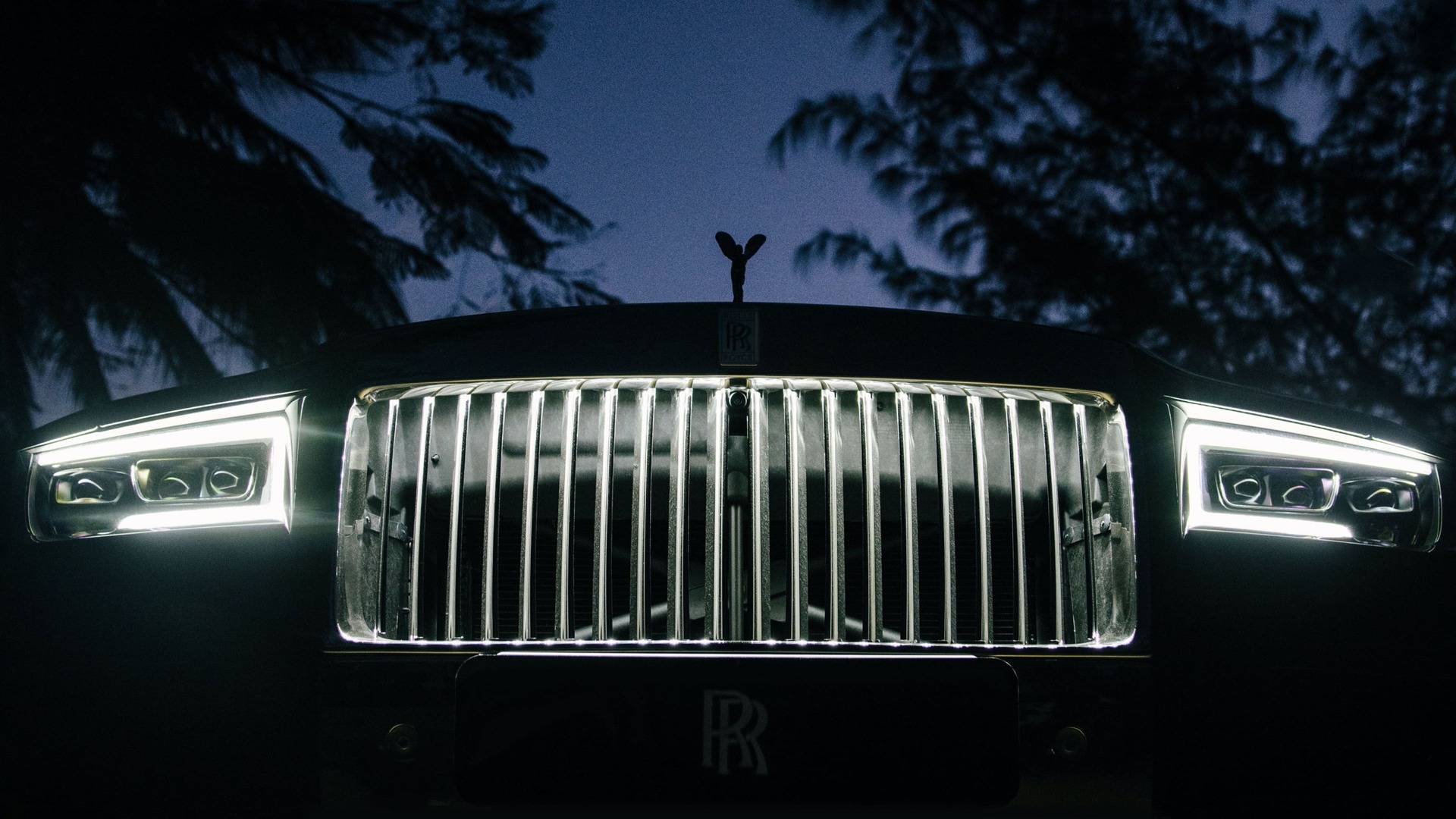 Close front view of Rolls-Royce motor car's illuminated grille at night.
