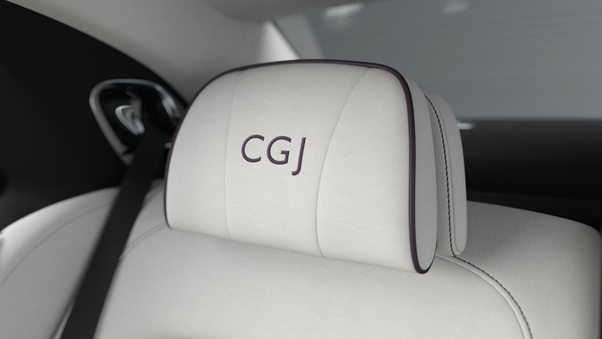An interior shot of a Rolls-Royce motor car white headrests with conform cushions and elegantly embroidered personalised lettering saying C.G.J.
