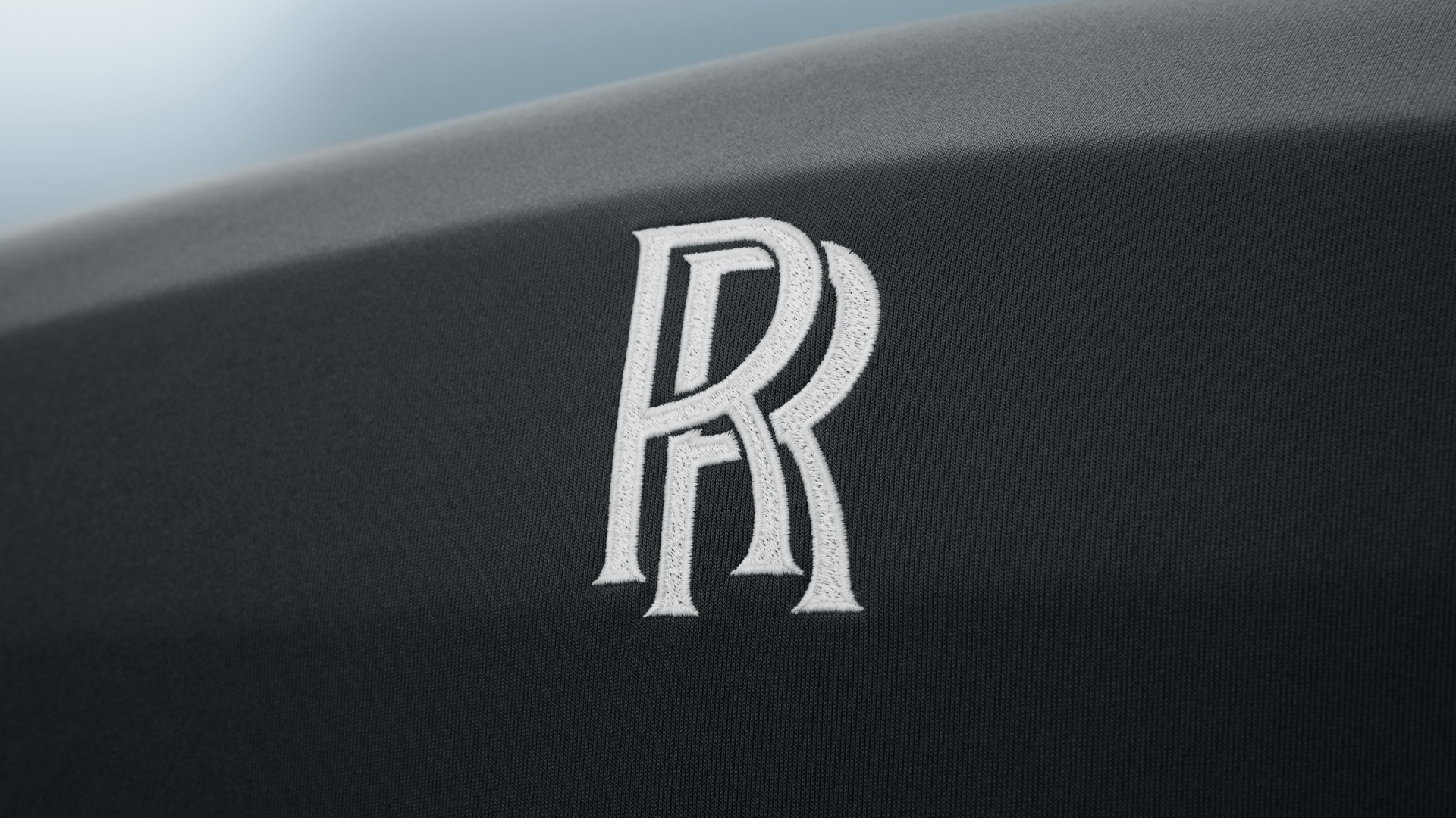 Detailed view of the embroidered RR monogram on the front of the Rolls-Royce car cover in black colour