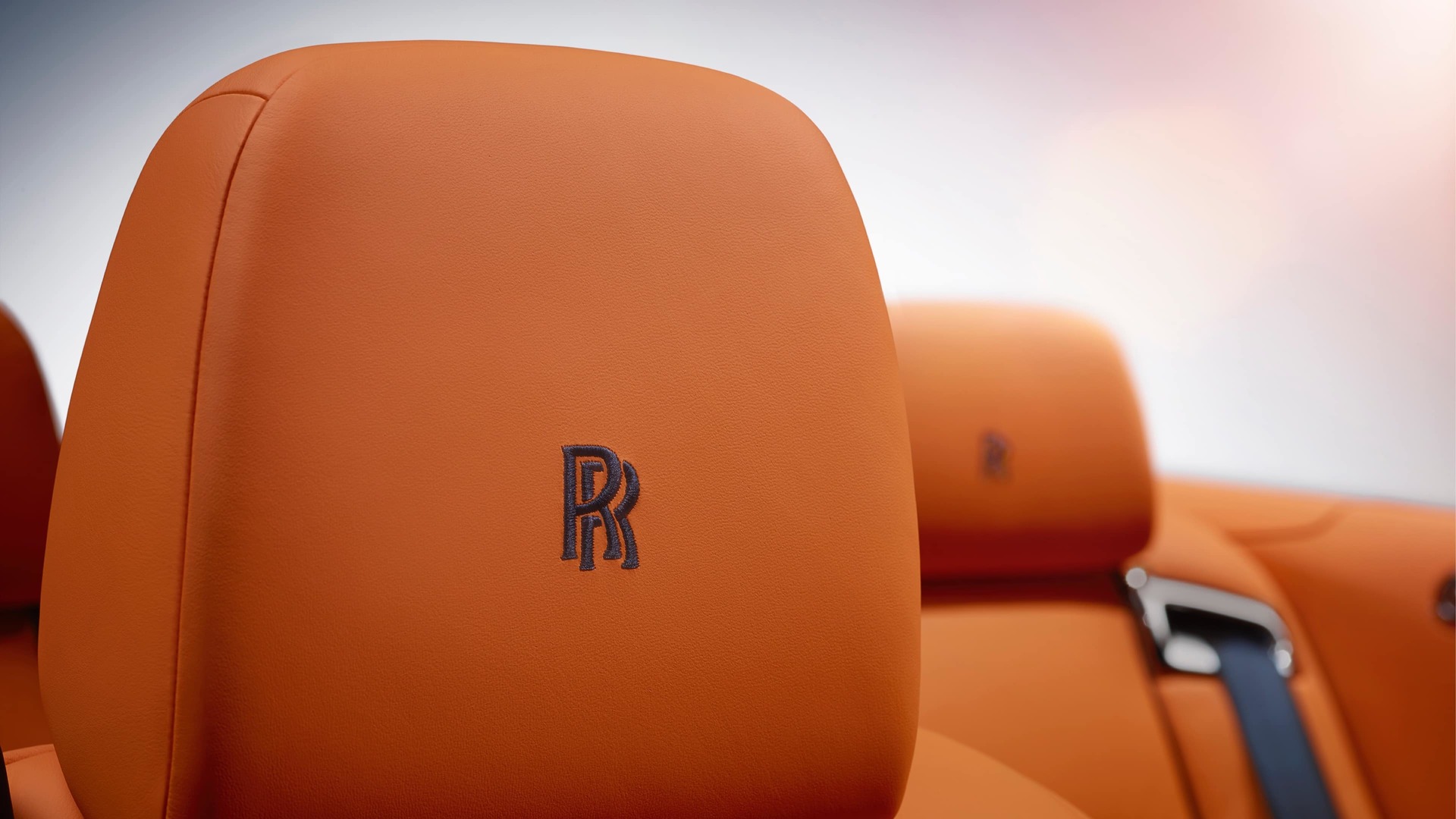 Signature black Rolls-Royce monogram embroidered onto leather headrests of a Rolls-Royce motor car