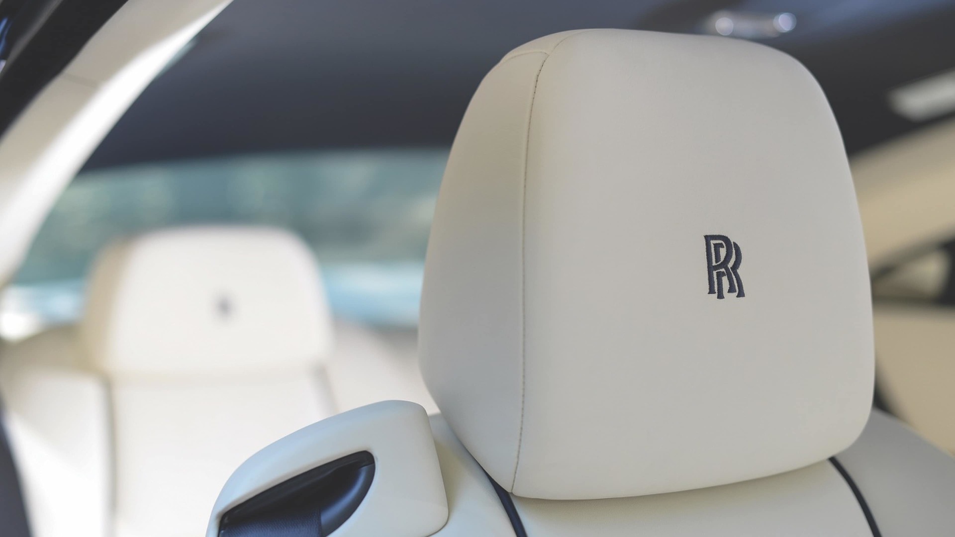 A close-up shot of a white Rolls-Royce Motor Cars headrest embroidered with a black Rolls-Royce monogram