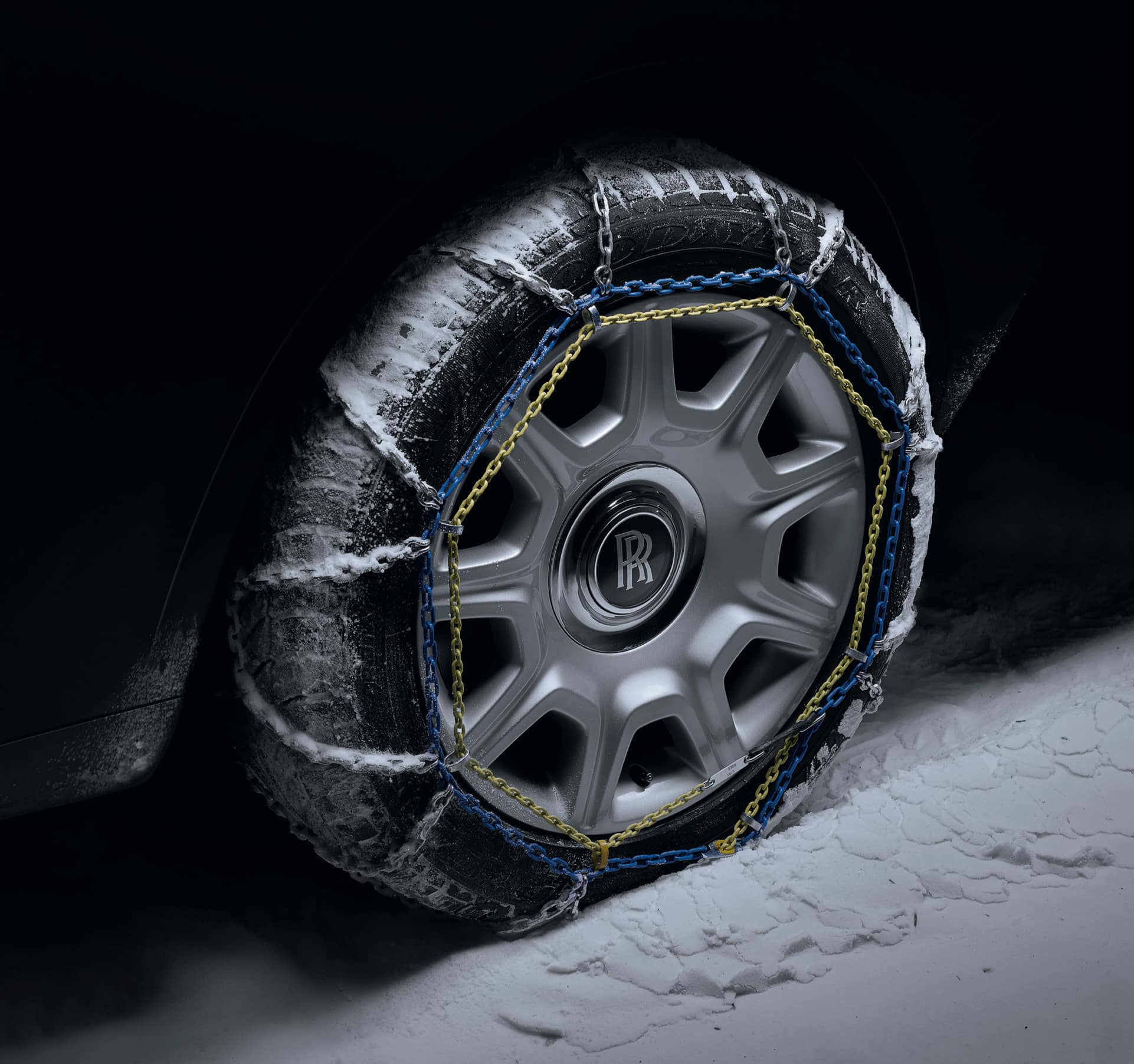 Snow chains on Rolls-Royce motor car with signature monogram on wheel