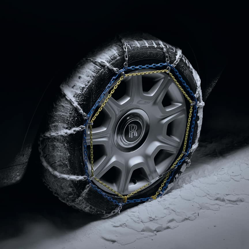 Snow chains on Rolls-Royce motor car with signature monogram on wheel