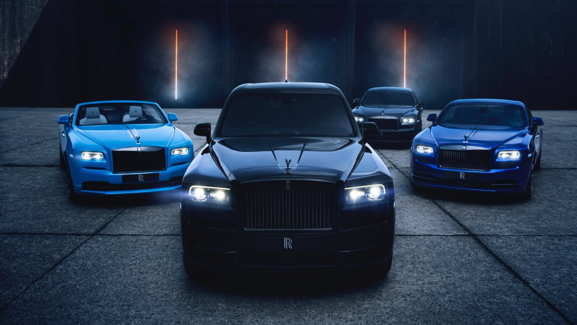 Multiple Rolls-Royce Motor Cars showing the different available Black Badge models - a light blue Dawn, Black Cullinan, dark blue Wraith and black Ghost