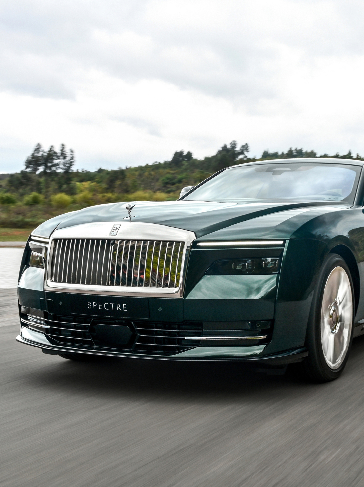 Front angled shot of a green Spectre driving fast.