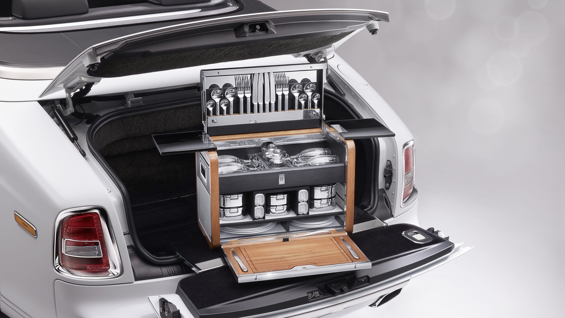 The handcrafted Rolls-Royce Picnic Hamper open inside the trunk of a Rolls-Royce motor car