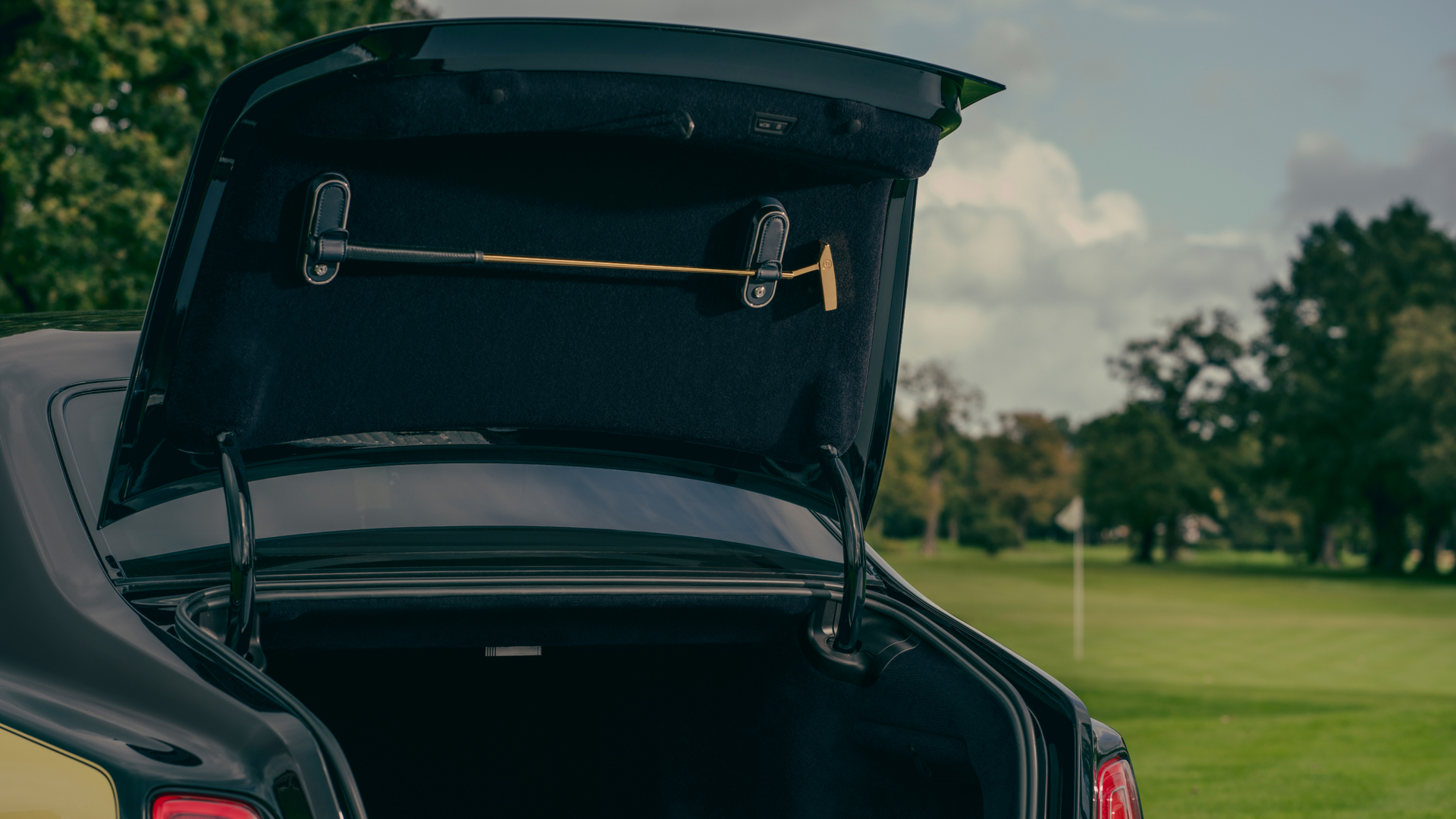 Image of the opened Goldfinger trunk with a gold golf putter attached to the roof of the trunk.