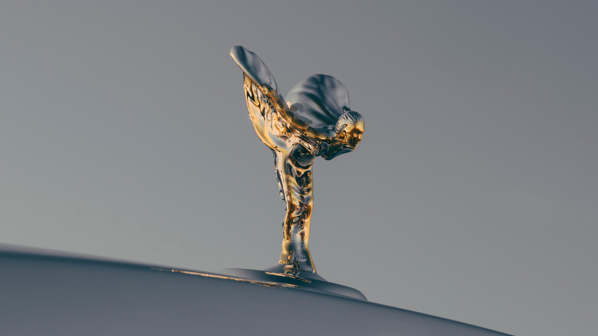 Close up of the gold Spirit of Ecstasy with the Rolls Royce logo just below.