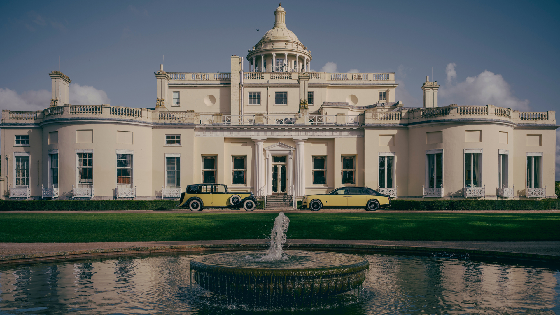 Image of the new and 60's model of the Phantom Goldfinger facing each other with a cream mansion in the background.
